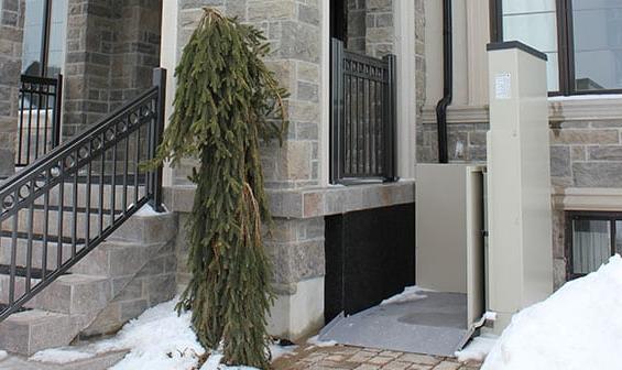 Outdoor Vertical Wheelchair Lift attached to stone patio